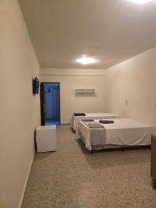 a hospital room with three beds and a blue door at Ideal Center in Nova Serrana
