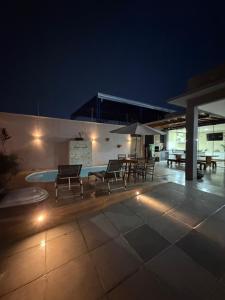 a patio with chairs and a pool at night at casa conforto e piscina in Sinop