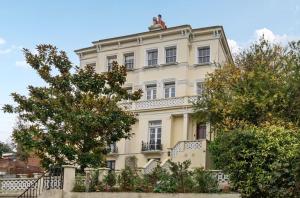 a large white building with a balcony and trees at Charming Garden Flat in Kent
