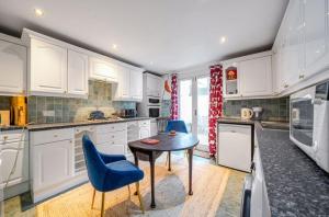 a kitchen with a table and two blue chairs at Charming Garden Flat in Kent