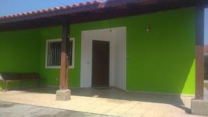 a green building with a white door and a green wall at Casa Garcia in Ilha Comprida