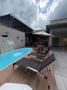 a pool with chairs and a table and an umbrella at casa conforto e piscina in Sinop