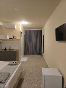 a room with a bed and a tv and a kitchen at Ideal Center in Nova Serrana