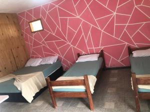 two beds in a room with a pink wall at Casa da mãe joanna in Guapimirim