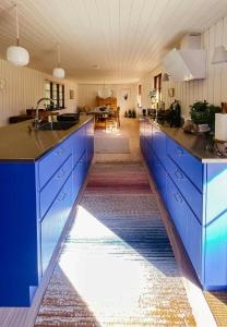 a kitchen with blue cabinets and a living room at Thatched Hideaway At Svinkløv Forest Edge in Fjerritslev
