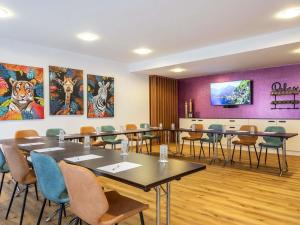 a room with tables and chairs and paintings on the wall at Mercure Hotel Bad Oeynhausen City in Bad Oeynhausen