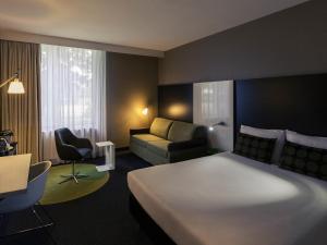 a hotel room with a large bed and a couch at Mercure Hotel Zwolle in Zwolle +84 photos