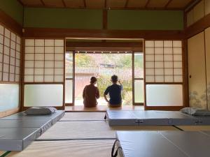 two people sitting in a room looking out the window at Hostel Kumano Kodo in Tanabe