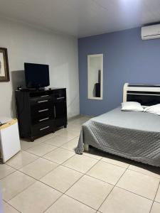 a bedroom with a bed and a flat screen tv at Pousada do pc in Bom Jesus do Itabapoana
