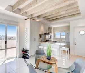 a dining room and kitchen with a glass table and chairs at Atlantic Canvas - Mountain and Sea in Cape Town