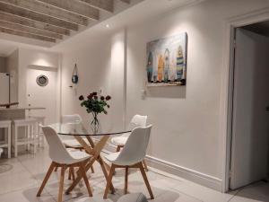 a dining room with a table and white chairs at Atlantic Canvas - Mountain and Sea in Cape Town