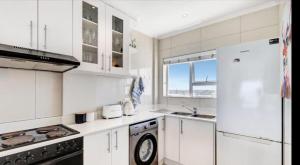 a white kitchen with a sink and a refrigerator at Atlantic Canvas - Mountain and Sea in Cape Town
