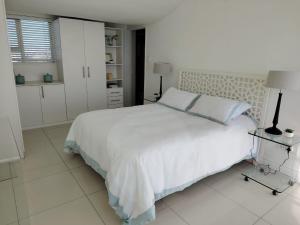 a white bedroom with a white bed and a window at Atlantic Canvas - Mountain and Sea in Cape Town +13 photos
