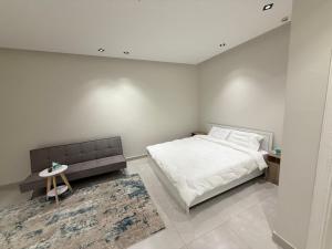 a white bedroom with a bed and a bench at comfortable hotel in Jeddah