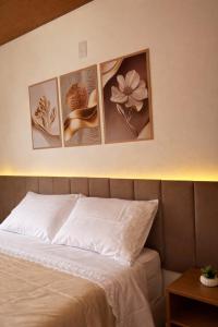 four pictures of flowers on a wall above a bed at Chalés do Lago Lumiar in Nova Friburgo