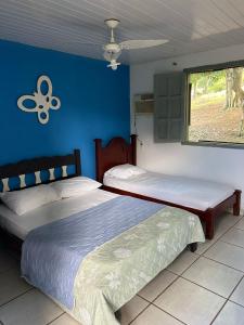 two beds in a bedroom with a blue wall at Pousada do pc in Bom Jesus do Itabapoana