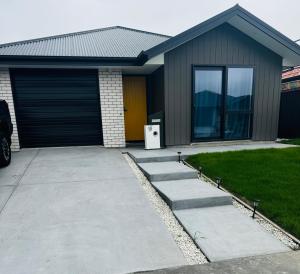 a house with a driveway and a garage at Room with en-suite bathroom in Kaiapoi