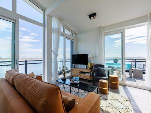 a living room with a couch and a television at Penthouse with beach view in Sint Annaland