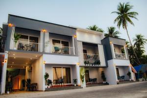 a large white building with a palm tree in the background at Horizon Nest in Agatti