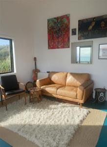 a living room with a brown leather couch and a rug at Epic Ocean Views & Outdoor bath in Wellington
