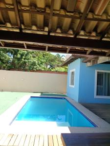 a swimming pool with a blue wall and a wooden deck at Recanto da gell in Búzios