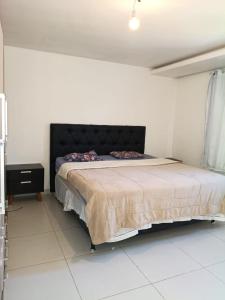 a bedroom with a large bed with a black headboard at Recanto da gell in Búzios +10 photos