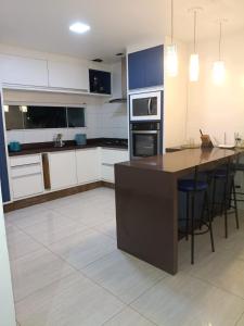 a kitchen with white cabinets and a large island with chairs at Recanto da gell in Búzios