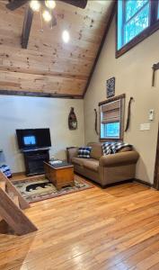 a living room with a couch and a tv at Couples Getaway Cabin with a Loft Bed - Firepit - Creek Access in Dahlonega
