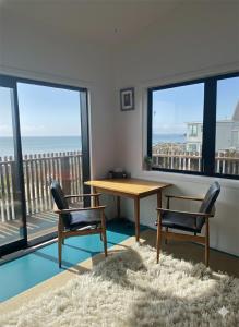 a table and chairs in a room with a view of the ocean at Epic Ocean Views & Outdoor bath in Wellington