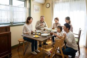 a group of people sitting around a table eating at KANEAGE BASE 14名までokの大型一棟貸し 家族旅行 合宿遠征 長期滞在に 海浜公園大洗20分 in Hitachinaka