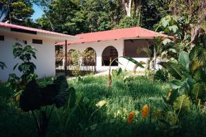 a garden in front of a building with a red roof at Taki Tambo Lodge in Tarapoto +32 photos