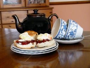 two sandwiches on a plate on a table with a tea pot at Bracken Cottage-B5817 in Wheddon Cross
