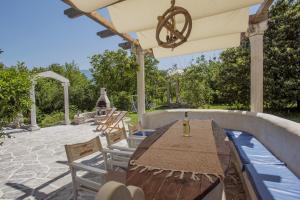 a patio with a wooden table and chairs and an umbrella at Villa Paradiso in Donji Morinj