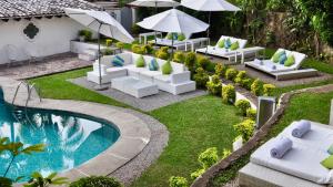 an outdoor patio with white furniture and a swimming pool at Las Casas B&B Boutique Hotel, Spa & Restaurante Cuernavaca in Cuernavaca