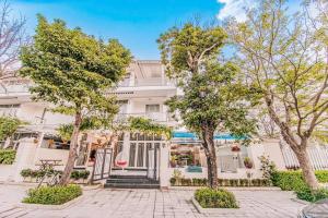 a white building with trees in front of it at Happy Villa in Sầm Sơn