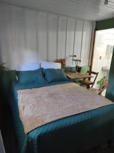 a bedroom with a bed with blue sheets and a table at Canto da restinga in Paranaguá