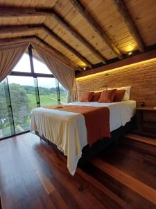 a bedroom with a large bed with a large window at Cabana Morro das Pedras in Armazém