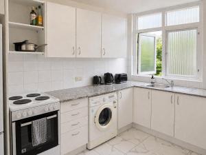 a kitchen with white cabinets and a washer and dryer at Sydney Harbour Side Waterfront Apartment in Sydney