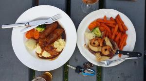 two plates of food with sausage and vegetables on a table at white hart hotel murrurundi in Murrurundi