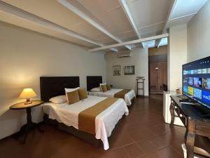 a hotel room with two beds and a flat screen tv at Posada El Remanso de Pueblo Nuevo in San Cristóbal