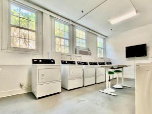 a kitchen with white appliances and a table and windows at The Green Room - Pool View with Parking Spot at 1920s Historic Residence with 24x7 Reception Desk on Palm Beach Island in Palm Beach