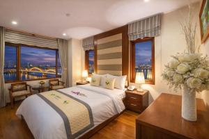 a bedroom with a large bed with a vase of flowers at Moonlight Hotel & Suites - Highfloor view of the city center and Dragon Bridge in Danang