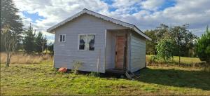 a small white house in a field of grass at Cabaña Evaristo Ivan in Frutillar