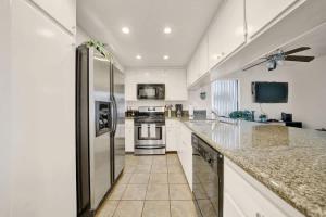 a kitchen with white cabinets and a stainless steel refrigerator at Contemporary Value Duplex with Rooftop Deck- 303 home in Newport Beach