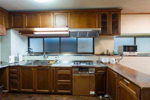 a kitchen with wooden cabinets and a stove top oven at 勝山恐竜博物館まで車で10分最大10名様ふとん屋の宿 悦 in Katsuyama +19 photos