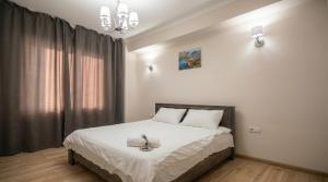 a bedroom with a bed with white sheets and a chandelier at Cozy Almaty Escape in Almaty