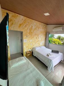a room with two beds and a tv and a window at Pousada Shamah - Morro de São Paulo in Morro de São Paulo