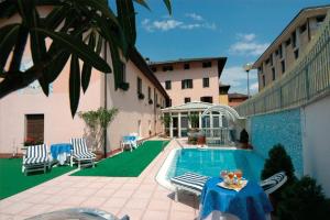 a pool with a table and chairs next to a building at Albergo Due Spade in Caldonazzo