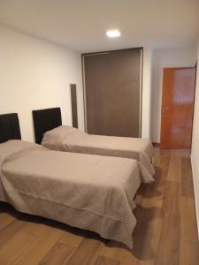 two beds in a room with wooden floors at Renzo 1 in Deán Funes