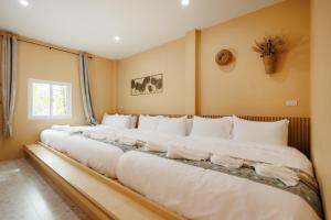 a row of white beds in a room at เพลาวิลล่า in Langu